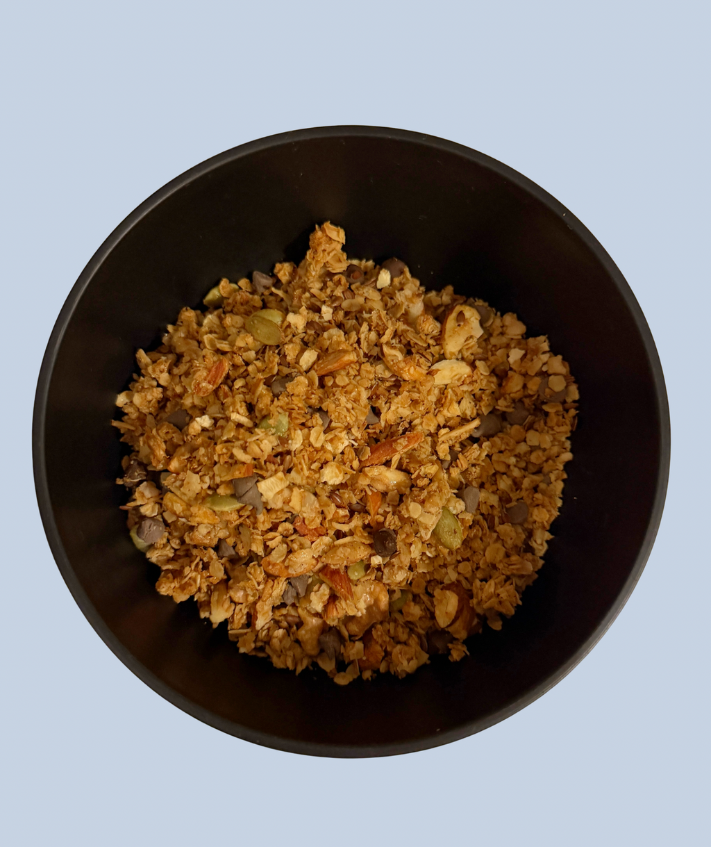 Black bowl filled with granola on a light blue background